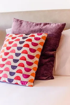 a pillow sitting on top of a white couch with a colorful pillow at Quinta do Paiva - Jardins do Vale in Roja- Pé