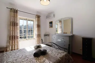 a bedroom with a bed with a dresser and a mirror at Golden Rana Apartment in Albufeira