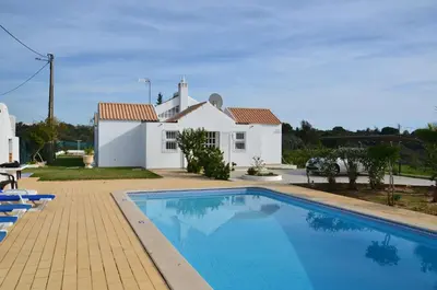 a villa with a swimming pool in front of a house at Villa Batista in Guia