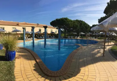 a swimming pool with blue water and umbrellas at Excelente T1 Oura Beach Bicos Apartment Lucia in Albufeira