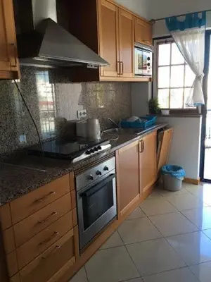 a kitchen with wooden cabinets and a stove top oven at Excelente T1 Oura Beach Bicos Apartment Lucia in Albufeira