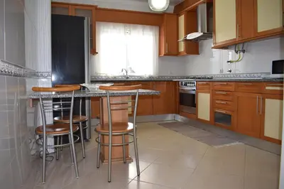 a kitchen with wooden cabinets and bar stools at Casa Sol da Falesia in Albufeira