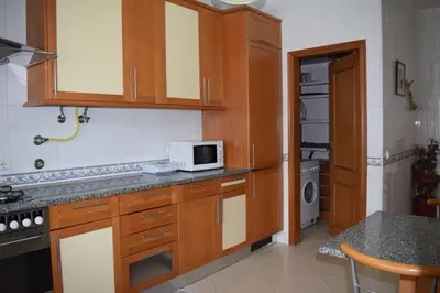 a kitchen with wooden cabinets and a microwave at Casa Sol da Falesia in Albufeira