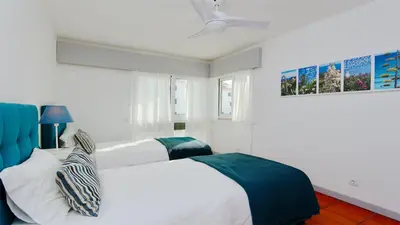 a white bedroom with two beds and a blue chair at Palmeiras do Golfe 160 - Clever Details in Vilamoura