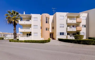 a white apartment building with a palm tree and a street at Ribas - Cozy 2 bedroom apartment - Vilamoura in Vilamoura