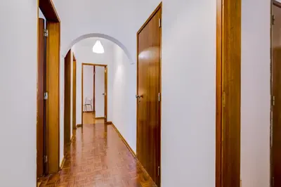 an arched hallway with wooden doors and a tile floor at Casa da Esquina - Faro city center in Faro