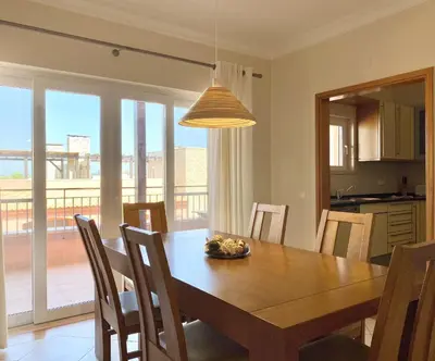 a kitchen and dining room with a wooden table and chairs at Amazing 2Bedroom apartment in Victoria Boulevard in Vilamoura