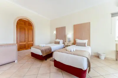 a hotel room with two beds and a tv at Quinta das Laranjeiras in Boliqueime