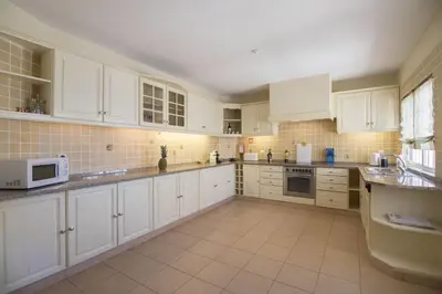a large white kitchen with white cabinets and appliances at Villa Caravela in Almancil