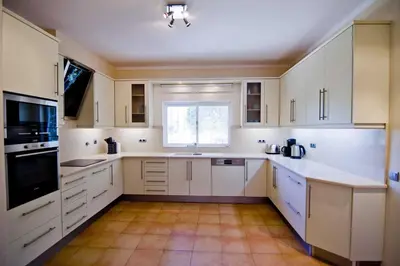 a kitchen with white cabinets and a window at Villa Jasmim in Almancil