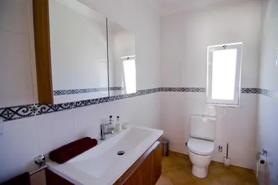 a bathroom with a white sink and a toilet at Villa Jasmim in Almancil