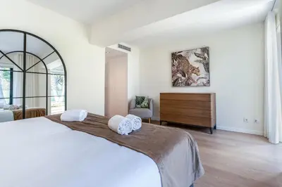 a white bedroom with a large bed and a dresser at Villa Natura in Vilamoura