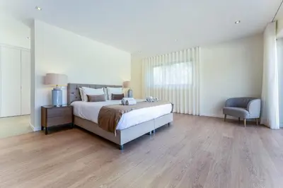 a bedroom with a large bed and a chair at Villa Natura in Vilamoura