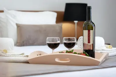 a bottle of wine and two glasses on a bed at Casa Clara in Vilamoura