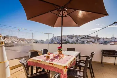 a table and chairs with an umbrella on a balcony at ★Traditional House★Heart of Oldtown★ Amazing views in Albufeira