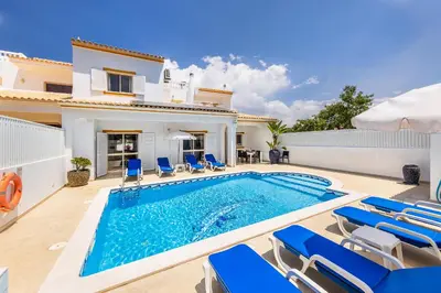a villa with a swimming pool and blue chairs at Villa Chiquito Albufeira - Private Pool&Parking - BBQ&AC&WI-FI in Albufeira
