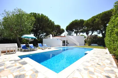 a swimming pool with chairs and a villa at Delightful single-storey villa, private pool, free air conditioning and wifi in Vilamoura