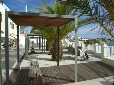 a pavilion with a palm tree and people sitting on a bench at Casa da Vila in Albufeira
