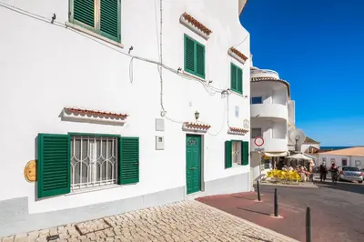 a street with white buildings with green shutters at Casa da Vila in Albufeira