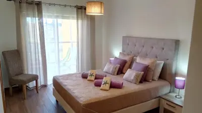 a bedroom with a large bed with purple pillows at Albufeira Premium Apartment in Albufeira