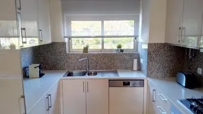 a kitchen with white cabinets and a sink and a window at Albufeira Premium Apartment in Albufeira