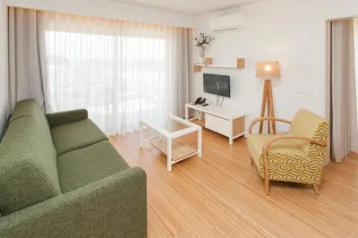 a living room with a green couch and a chair at Alfagar Aparthotel in Albufeira