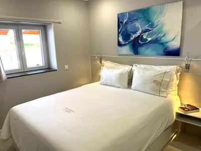 a bedroom with a white bed with a painting on the wall at Villa Bellevue in Albufeira