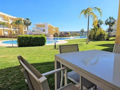 a white table and chairs with a view of a pool at Albufeira Prime Apartment in Albufeira
