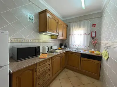 a kitchen with wooden cabinets and a microwave at VILLA EBER - independent 1 & 2 bedroom apartments, pool, air con, fast Wi-Fi, near old town of Albufeira and beaches in Albufeira