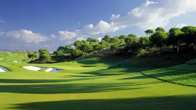 a lush green golf course with trees and a hill at Luxury 3 Bedroom Apartment on Gated Complex in Quarteira