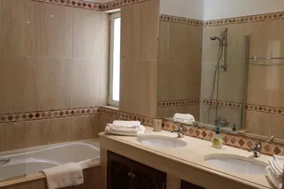 a bathroom with two sinks and a tub and a mirror at Luxury 2 Bedroom Apartment with Private Garden in Almancil