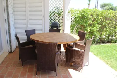 a wooden table and chairs on a patio at Luxury 2 Bedroom Apartment with Private Garden in Almancil