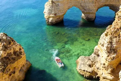 a boat in the water next to an arch in the ocean at Cool Grey Albufeira in Albufeira