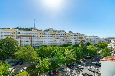 an apartment building with cars parked in a parking lot at Cool Grey Albufeira in Albufeira