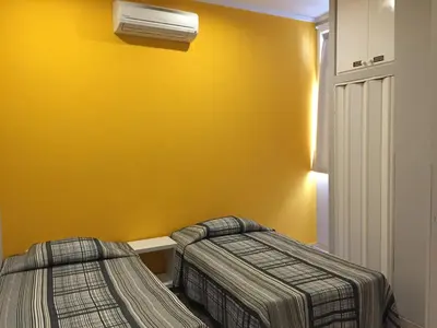 two beds in a room with a yellow wall at Guest House Sao Filipe in Faro