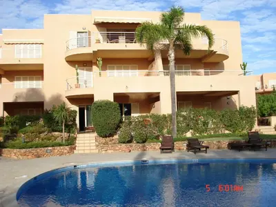 a building with a palm tree and a swimming pool at Citadela I, Golfe, Pool and Falesia Beach in Vilamoura