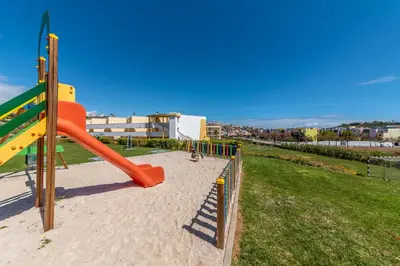 a playground with an orange slide in a park at Jardins Marina Stars in Albufeira