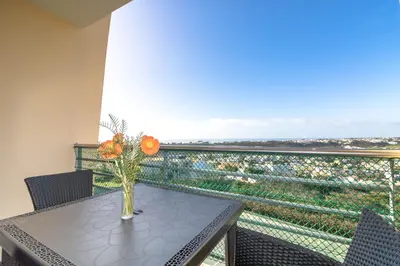 a table with a vase of flowers on a balcony at #004 Orada by Home Holidays in Albufeira