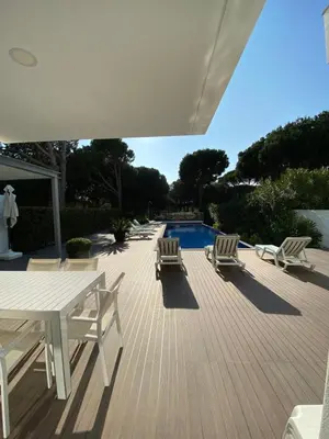 a deck with chairs and a table and a pool at Amora Villa - Vilamoura in Vilamoura