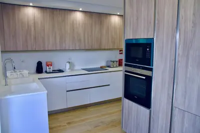 a kitchen with white cabinets and a black microwave at Amora Villa Sacha in Vilamoura