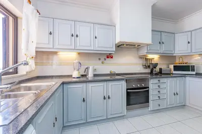 a kitchen with white cabinets and a sink at Villa Mirante in Albufeira