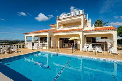 a villa with a swimming pool in front of a house at Villa Mirante in Albufeira
