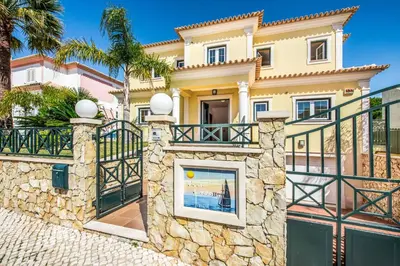 a large yellow house with a gate and a fence at Villa Luana in Olhos de Água