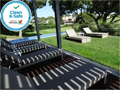 a group of chairs and a sign in a yard at Apartamento com 3 quartos e piscina in Vale do Lobo