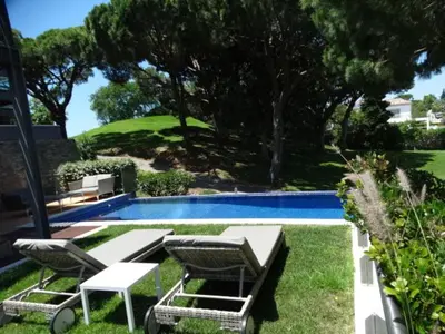 a swimming pool with two chairs and a table and a table and chairs at Apartamento com 3 quartos e piscina in Vale do Lobo