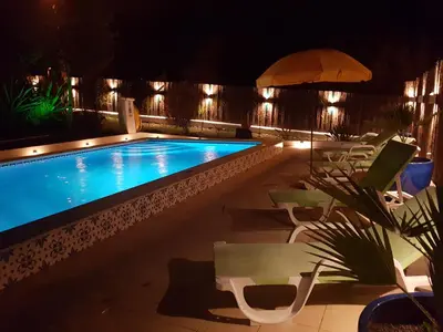 a swimming pool at night with chairs and umbrellas at villa yvonne,private pool,private parking 1,7 km from the beach in Albufeira
