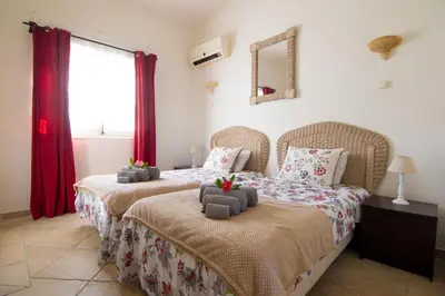 two beds in a bedroom with red curtains at villa yvonne,private pool,private parking 1,7 km from the beach in Albufeira
