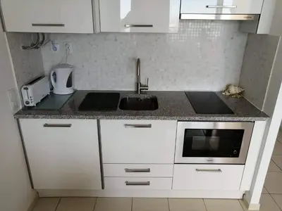 a white kitchen with a sink and a microwave at Sea View 3 in Albufeira