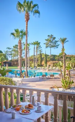 a table with food on a balcony next to a pool at PortoBay Blue Ocean in Albufeira
