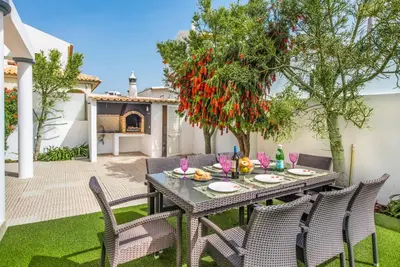 a patio with a table and chairs and a tree at Villa Jomar in Guia